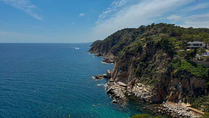 A beautiful ocean view with a rocky shoreline. The water is calm and the sky is clear