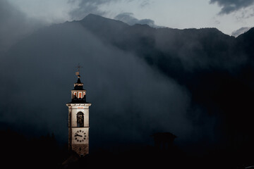 old church tower of Rasa, Switzerland in front of mountains in a thunderstorm
