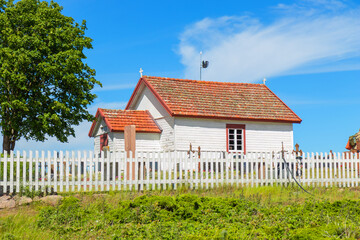 White wooden church in sunlight. Nordic architecture, rural Finnish village, peaceful atmosphere, Christian heritage, and traditional northern culture