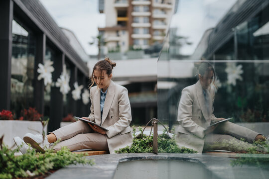 Stylish person reading and reflecting in an outdoor urban environment surrounded by greenery and contemporary architecture - Powered by Adobe