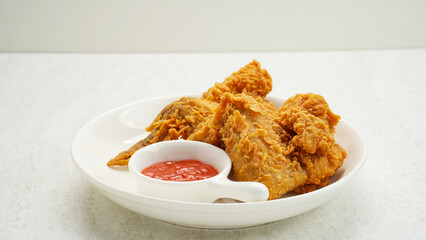 Crispy fried chicken wings served with chilli sauce on white plate