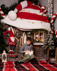 A boy sits near a New Year's house with a rabbit in his hands.