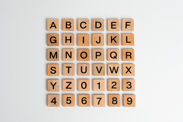Alphabet letters and numbers on scrabble wooden pieces, isolated on white. © Luqman Aditiamala