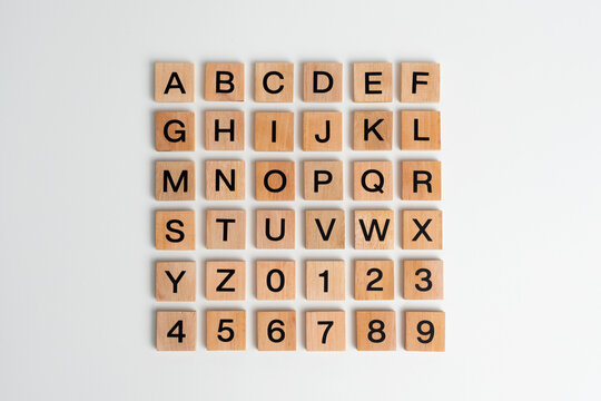 Alphabet letters and numbers on scrabble wooden pieces, isolated on white.