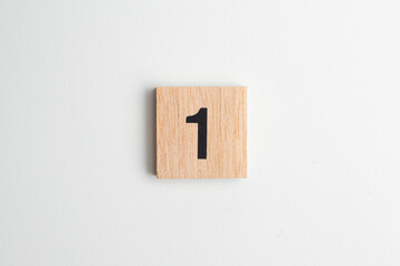 Single wooden block with the number "1" printed in black on a white isolated background. Educational toy for children learning numbers or for creative design and math concepts.