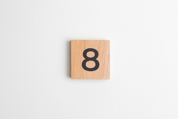 Single wooden block with the number "8" printed in black on a white isolated background. Educational toy for children learning numbers or for creative design and math concepts.