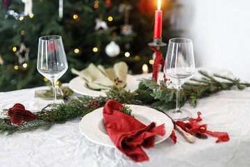 Stylish christmas table setting for family dinner. Elegant plate with napkins, cutlery, glassware,...