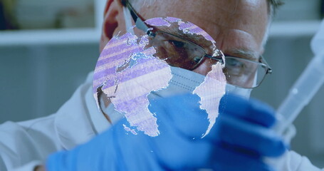 Scientist pipetting vial in lab, wearing lab coat, mask and eyeglasses with digital globe hologram