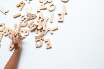 Caucasian child playing with wooden alphabet letters on white background