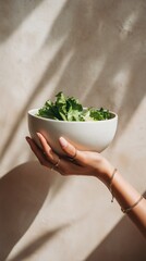 female hand holding bowl of fresh vegetables with minimal lifestyle style