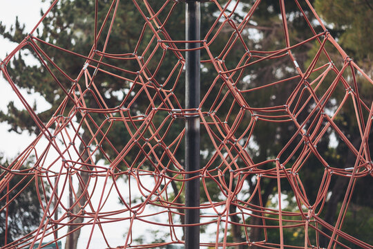 Climbing adventure at sunset in a playground with a colossal rope net structure surrounded by lush greenery - Powered by Adobe