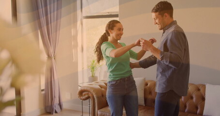 Dancing couple twirling in home living room, with brown leather sofa and potted plant