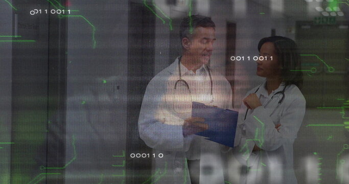 Standing two doctors consulting over blue clipboard in hospital corridor, with data overlay - Powered by Adobe