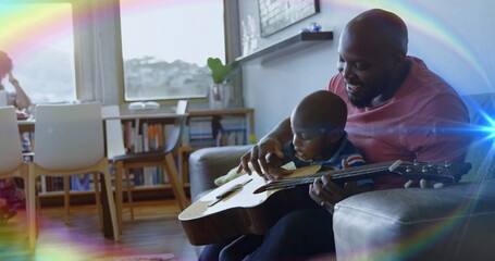 Guiding father and son learning guitar in modern home living area, with acoustic guitar, copy space