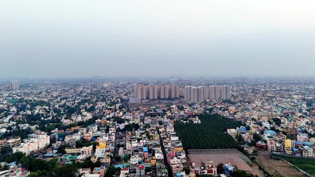 High-angle view of a bustling city. A modern high-rise building and a green patch sit within a dense urban tapestry. Excellent for showcasing urbanization and cityscapes.