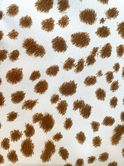 Closeup of fabric with brown animal print spots on white background. Stylish textile pattern inspired by leopard skin, perfect for fashion, upholstery, crafts, and decorative design projects.