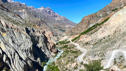 Travel to Tajikistan, Asia. Dangerous mountain serpentine roads. Magnificent view of the mountain range, through which a stormy river flows
