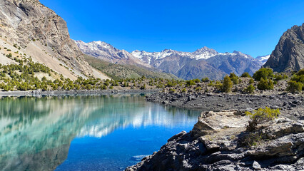 Naklejka premium Turquoise and blue water combine in the mysterious Alaudinsky Lake in the Fan Mountains of Tajikistan. Travel to hard-to-reach places