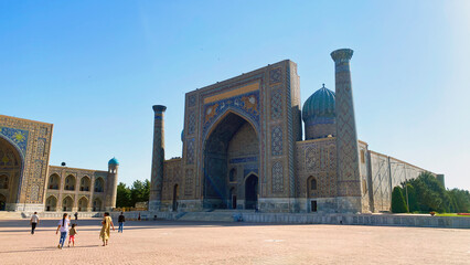 Sherdor Madrasah is one of the three majestic mosques of the Registan complex in Samarkand. A group of people walks in the main square of Samarkand