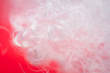 Extreme macro of polyester stable fiber on red background. Selective focus, shallow depth of field. Abstract dreamy background