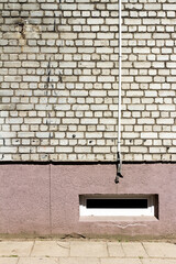 White brick wall with some cables and basement window. Architectural detail.