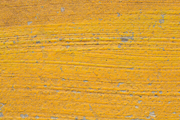 A horizontal close-up shot of a rough surface with yellow peeling paint and textured lines, serving as an abstract background