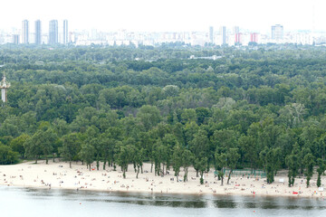 Asian polluted city smoke aerial top view of crowd of people on a beach coast line along river park green zone with panorama horizon background skyscrapers town living district area