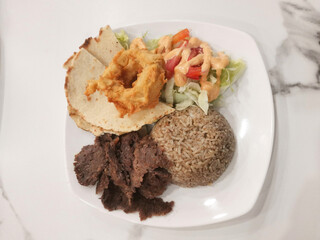 Delicious doner kebab platter with rice, salad and fried onion rings served elegantly