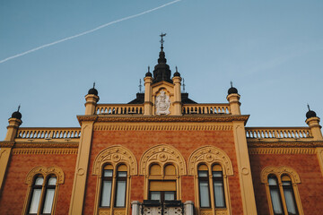 Fototapeta premium Ornate yellow orange facade of a historic building in Novi Sad, Serbia, captured in winter sunset light