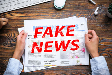 Woman reading newspaper at workplace on wooden background