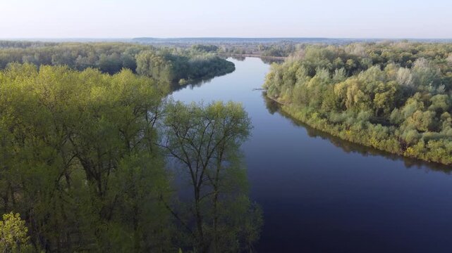 Spring landscape of the wide Desna river. Aerial video from a bird's eye view of the wide Desna river in spring, surrounded by trees and shrubs just beginning to bloom with the first leaves