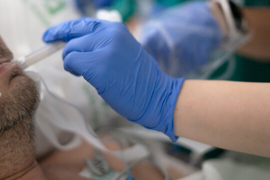 Nurse inserting a nasogastric tube into patient's nose in hospital room