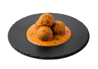 A dark gray slate plate holds a group of flavorful meatballs bathed in an orange-red sauce.
