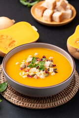 Butternut squash pumpkin soup in a bowl on black background, Homemade food in autumn season