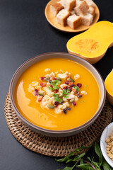 Butternut squash pumpkin soup in a bowl on black background, Homemade food in autumn season
