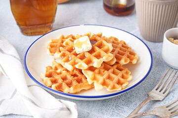 Plate of tasty waffles with maple syrup on white background