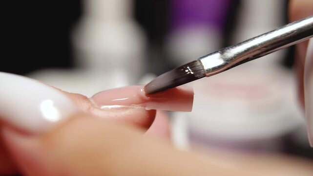 Manicure expert carefully leveling gel polish during extension procedure, creating smooth, even surface with professional technique.
