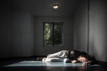 The High and The Low. A man lying on the floor in a dimly lit hallway. The image captures the loneliness, isolation, and desperation of drug addiction and homelessness.