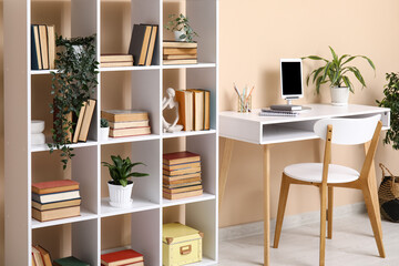 Interior of modern living room with workplace and bookshelf near beige wall