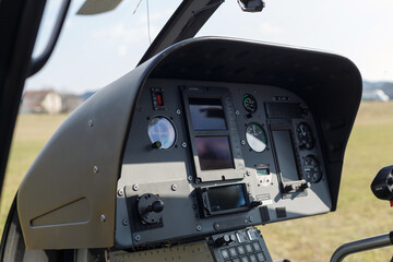 Instrument panel of a helicopter shows various controls and gauges, highlighting the cockpit during a daytime flight.
