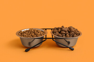 Bowls with different dry pet food on brown background