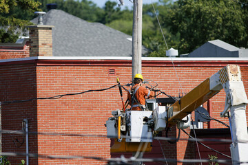 Un électricien travaille sur un poteau électrique avec un marteau-piqueur en arrière-plan. Un ouvrier travaille sur des fils électriques. Des ouvriers sur le chantier d'un transformateur haute tension