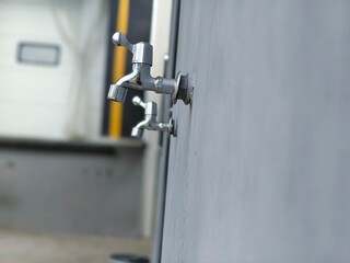 A row of outdoor water faucets on a plain wall, ready for public or utility use