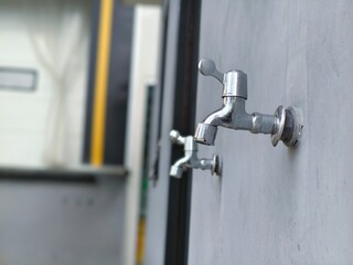 A row of outdoor water faucets on a plain wall, ready for public or utility use