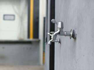 A row of outdoor water faucets on a plain wall, ready for public or utility use