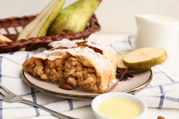 Plate with tasty pear strudel pieces and bowl of cream, closeup