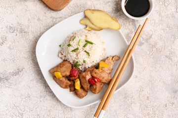 Delicious sweet and sour chicken with rice in plate near sauce on grey grunge background