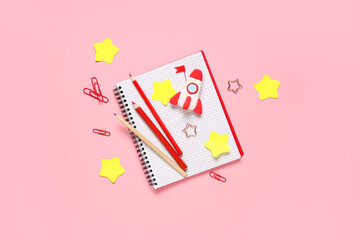 Rocket made of plasticine with notebook and pencils on pink background. Top view