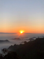 Sunrise over a misty valley with silhouetted hills and vibrant sky