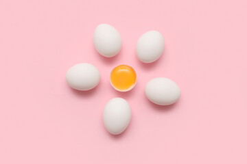 Whole and cracked chicken eggs on pink background